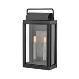 The Sag Harbor Outdoor 2 Light Medium Wall Lantern - Black is a rectangular fixture with a glass enclosure and two vertical light bulbs inside. It features a simple top handle, exuding modern elegance and durability.