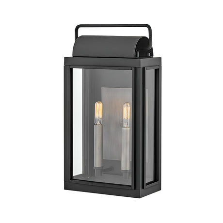 The Sag Harbor Outdoor 2 Light Medium Wall Lantern - Black is a rectangular fixture with a glass enclosure and two vertical light bulbs inside. It features a simple top handle, exuding modern elegance and durability.