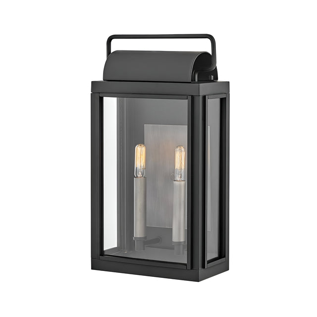 The Sag Harbor Outdoor 2 Light Medium Wall Lantern - Black is a rectangular fixture with a glass enclosure and two vertical light bulbs inside. It features a simple top handle, exuding modern elegance and durability.