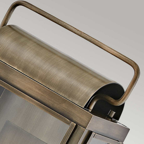 Close-up of the Sag Harbor Outdoor 2 Light Medium Wall Lantern, featuring a vintage-style, brushed metal finish with a curved handle. It showcases a rectangular shape with a rustic painted burnished bronze finish, highlighting its antique look. The image zooms in on the top section to emphasize its weather-resistant craftsmanship.