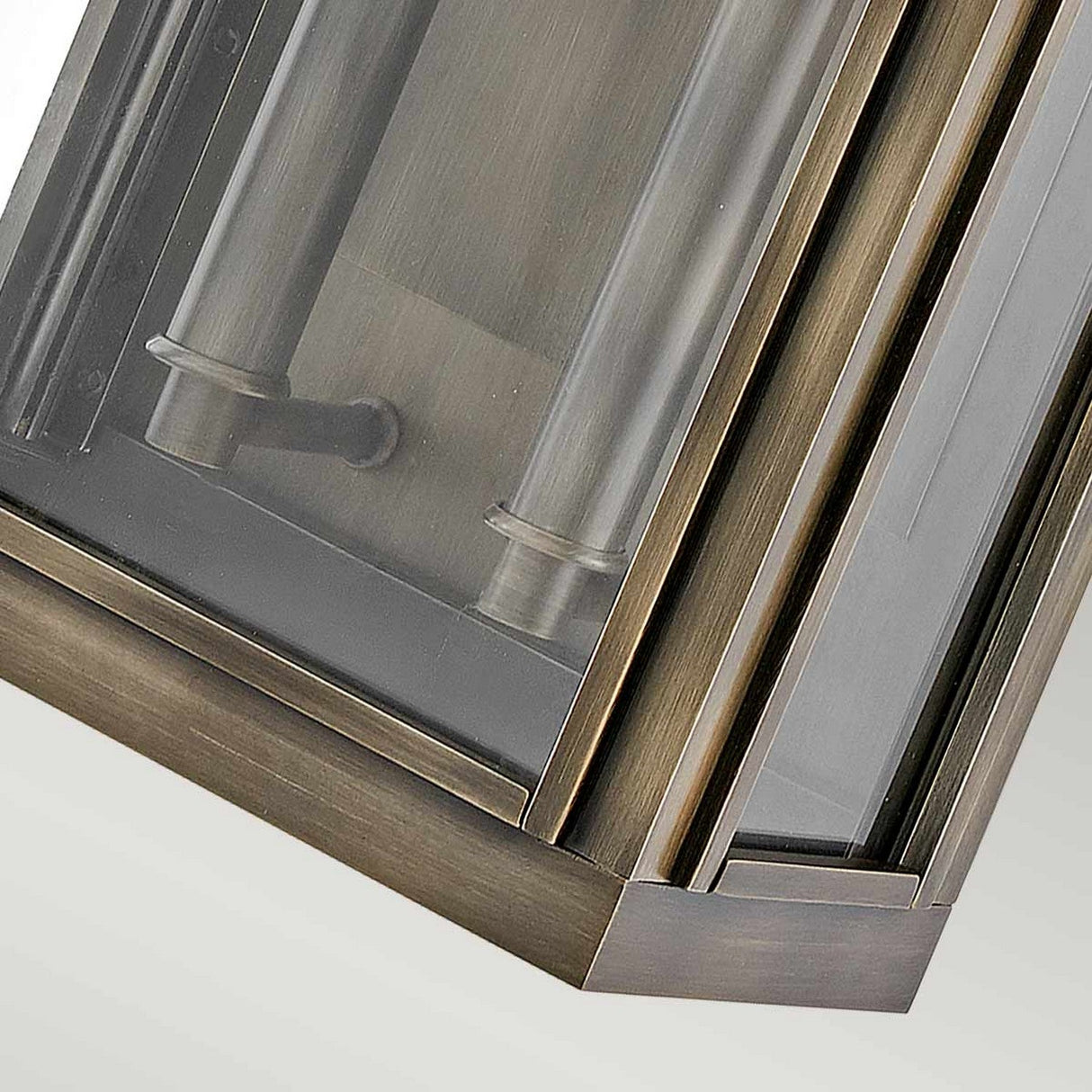 Close-up of the Sag Harbor Outdoor 2 Light Medium Wall Lantern – Painted Burnished Bronze, featuring a burnished bronze frame and rectangular glass panels that reveal cylindrical light fixtures inside. Positioned at an angle, this weather-resistant piece highlights its sleek and modern design.