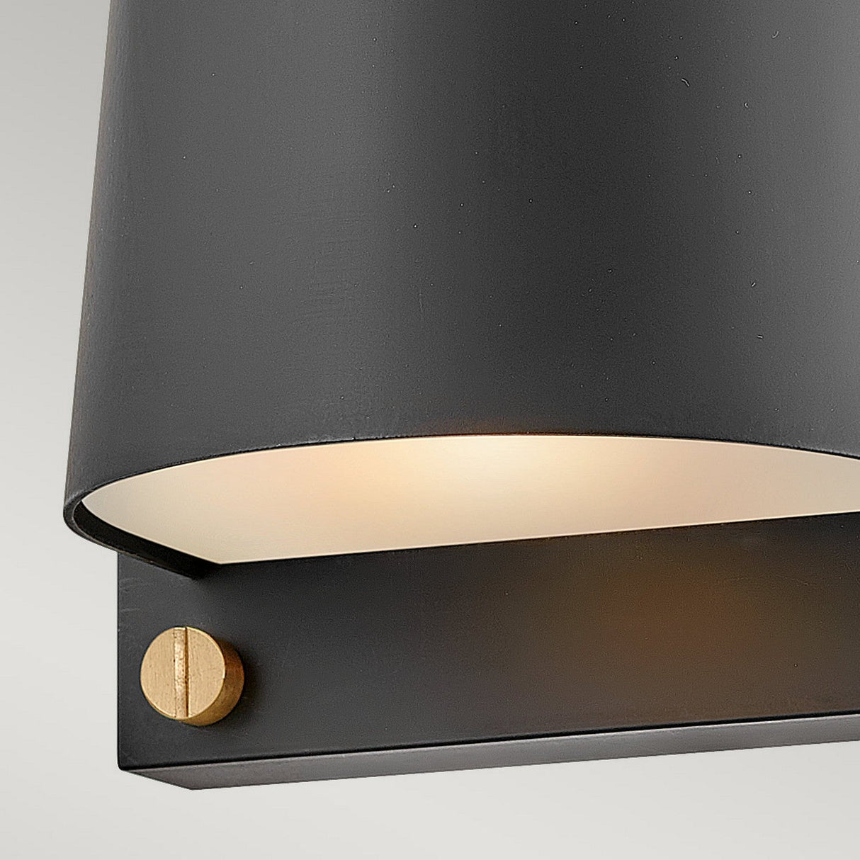 A detailed look at the Scout Outdoor 1 Light Small Wall Light in black reveals its minimalist design. The partially visible light emits a soft glow, and the fixture's small brass accent adds elegance. This weather-resistant wall sconce is ideal for outdoor use.
