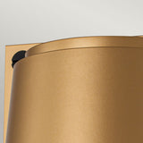 The image features a close-up of a metallic cylindrical object with a gold finish, similar to the Scout Outdoor 1 Light Small Wall Light in Painted Heritage Brass, set against a light background. It has a smooth surface and rounded top, with part of a black circular component subtly appearing like an element from the Scout Outdoor Lighting collection.