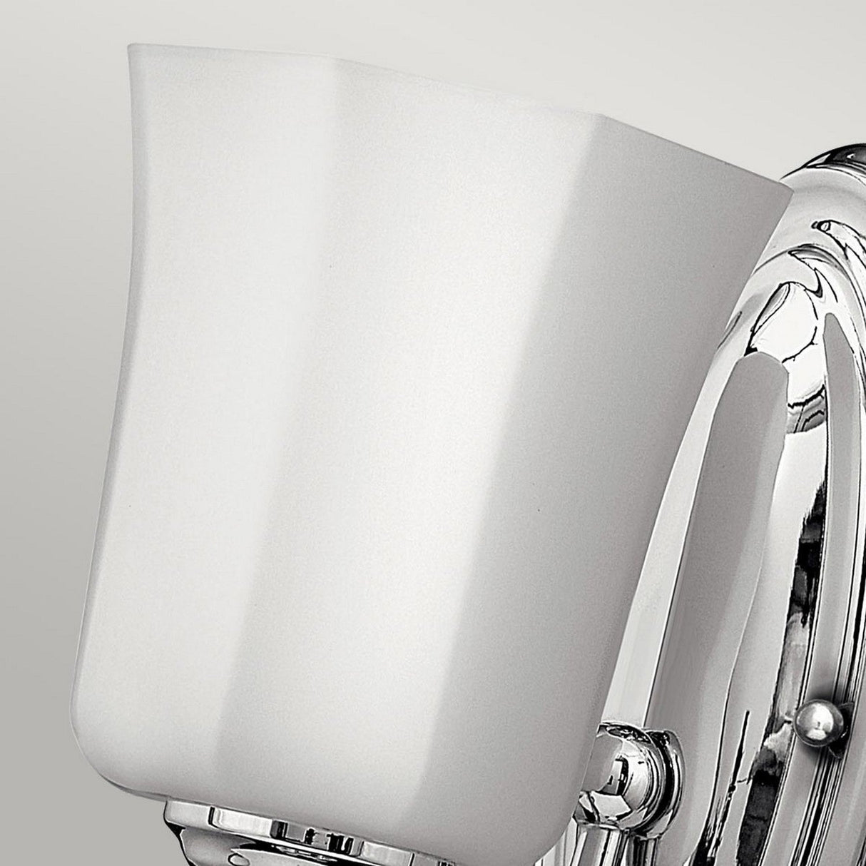 Close-up of the Shelly 1 Light Wall Light in polished chrome, showcasing its sleek fluted glass shade and minimalist, elegant design against a plain gray background.