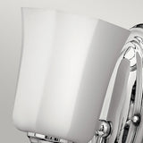 Close-up of the Shelly 1 Light Wall Light in polished chrome, showcasing its sleek fluted glass shade and minimalist, elegant design against a plain gray background.