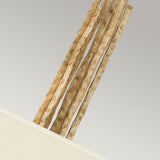 A close-up view features several textured, vertical elements emerging from a Champagne Gold box. These elements possess a rough, wavy surface and are light brown. The positioning of the box is in the bottom left corner against a simple, light-colored backdrop. This design pairs beautifully with various decor styles and is epitomized by the Spyre 6 Light Pendant in Champagne Gold.