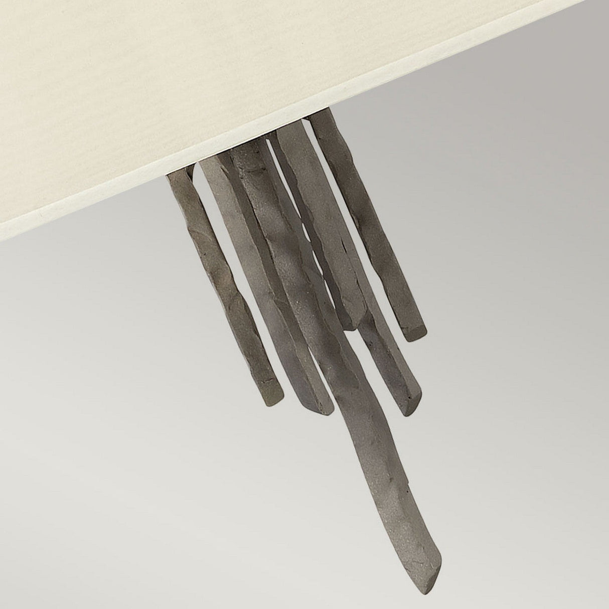 The Spyre 6 Light Pendant in Metallic Matte Bronze features a series of elongated, curved metal rods that hang from a beige surface. These rods are evenly spaced and slightly twisted, creating a modern and artistic look with industrial appeal.