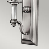 The Sussex 1 Light Wall Light in brushed nickel showcases a close-up of its elegant design, featuring a rectangular backplate and an artfully curved arm. Its detailed craftsmanship and polished finish lend a timeless elegance to the fixture, enhancing any space with sophistication.