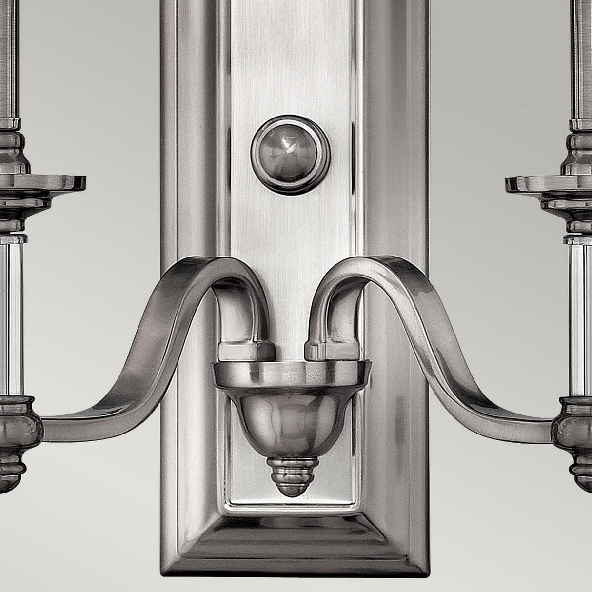 Here's a close-up of the Sussex 2 Light Wall Light - Brushed Nickel, a wall-mounted fixture that exemplifies contemporary elegance. It features curved arms and a central decorative element on a rectangular backplate, all finished in brushed nickel against a light gray background.