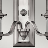 Here's a close-up of the Sussex 2 Light Wall Light - Brushed Nickel, a wall-mounted fixture that exemplifies contemporary elegance. It features curved arms and a central decorative element on a rectangular backplate, all finished in brushed nickel against a light gray background.