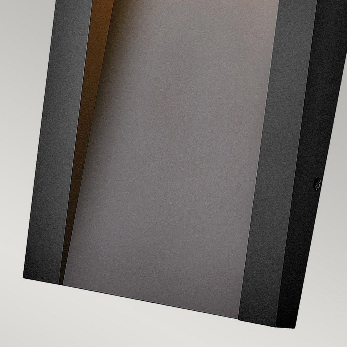 Close-up of the Taper Outdoor LED Small Wall Lantern - Black, featuring a sleek, rectangular design with a black frame and frosted glass center that offers energy-efficient lighting. The contemporary style showcases a slightly angled perspective, emphasizing its minimalist elegance against a neutral background.