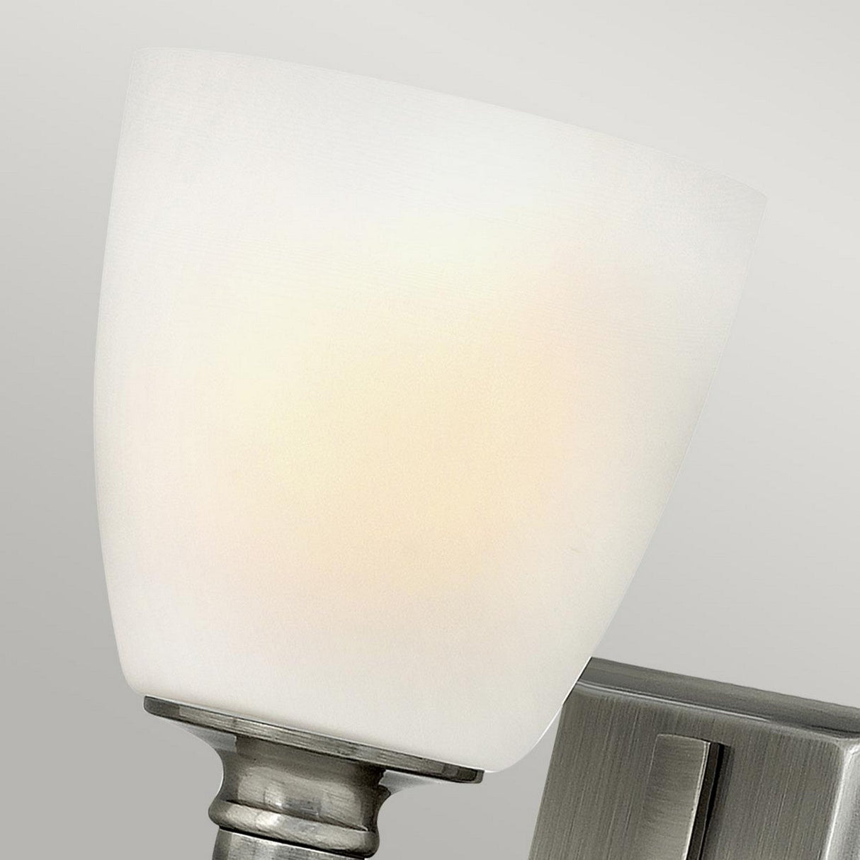 Close-up of the Truman 1 Light Wall Light in antique nickel, featuring an opal glass shade, set against a light gray background.