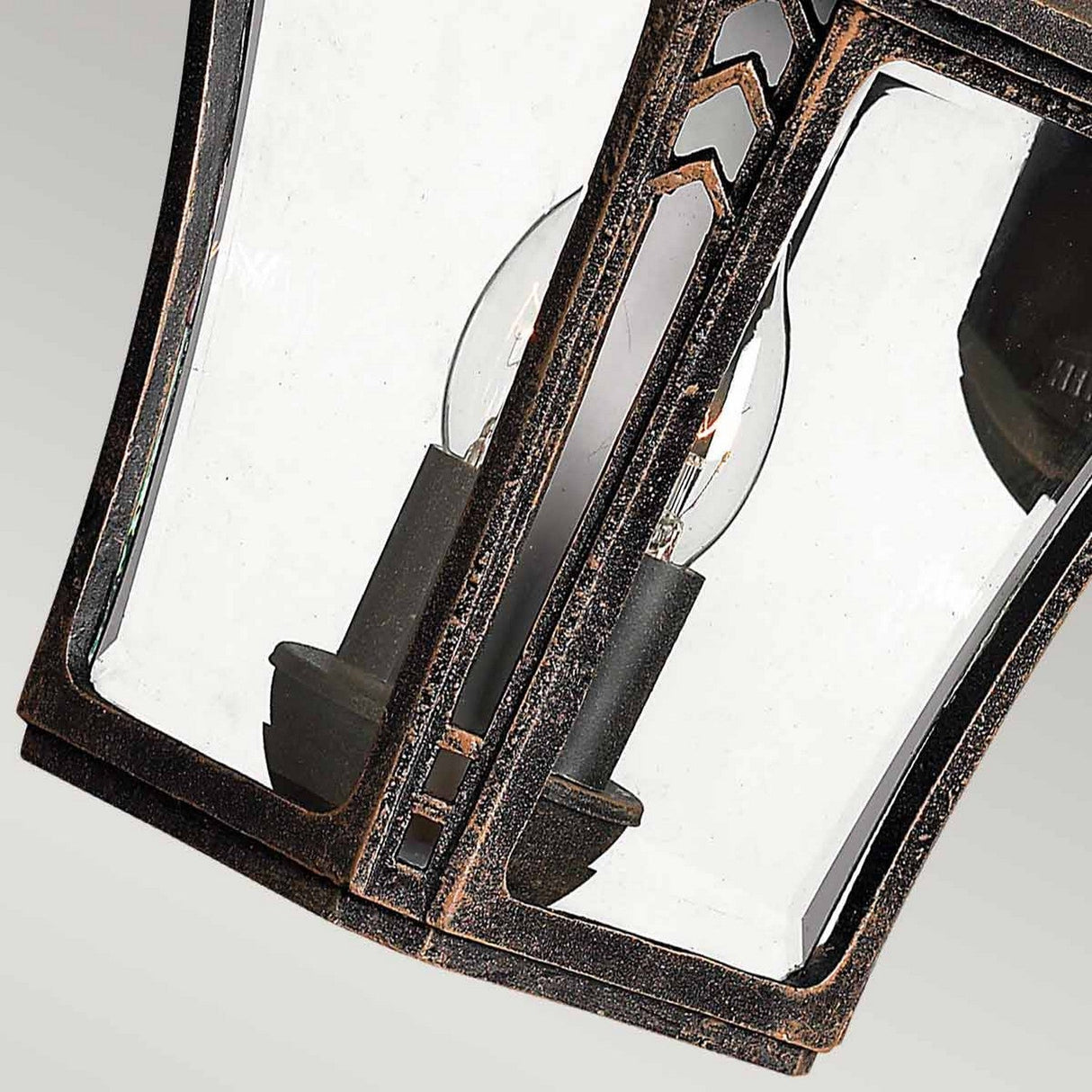 A detailed look at the Wabash Outdoor 2 Light Medium Wall Lantern - Bronze highlights its vintage-style allure. The lantern's metal frame, accented by a subtle chevron design, features a weathered rustic finish. Two exposed light bulbs within cast a welcoming glow through its sophisticated exterior, enhancing any environment.