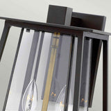 A close-up of the Walker Outdoor 2 Light Large Wall Lantern in bronze with heritage brass highlights its contemporary design. The sleek black metal frame encases clear glass panels, showcasing dual candle-style LED bulbs supported by a vertical brass rod, making it a striking feature in outdoor lighting design.