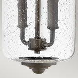 A close-up of the Willoughby 2 Light Wall Lantern - Oil Rubbed Bronze, showcasing its clear seeded glass cover adorned with air bubbles and revealing the metal components inside. The background remains plain and light-colored.