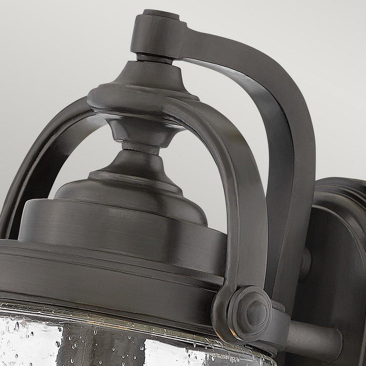 Close-up of the Willoughby 1 Light Wall Lantern, featuring a vintage-style curved metal frame and clear glass. The oil rubbed bronze finish and elegant design enhance the classic aesthetic, making it perfect for outdoor lighting.