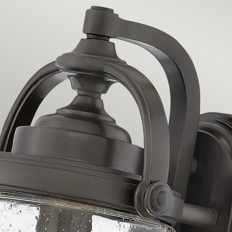 Close-up of the Willoughby 1 Light Wall Lantern, featuring a vintage-style curved metal frame and clear glass. The oil rubbed bronze finish and elegant design enhance the classic aesthetic, making it perfect for outdoor lighting.