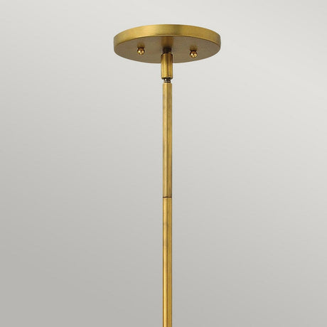 A close-up of the Zelda 1 Light Mini Pendant in Vintage Brass against a neutral background. The pendant features a rod extending down from a round, flat canopy, highlighting its simple and sleek mid-century design that adds timeless elegance to any space.