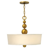 The Zelda 3 Light Pendant - Vintage Brass showcases a sleek, contemporary style with its modern brass pendant frame and fabric drum shade. The fixture is enhanced by three elegant brass spheres on the chain and a smaller one below, effortlessly merging with mid-century design elements.