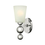 The Zelda 1 Light Wall Light - Polished Nickel showcases a polished nickel finish with a chrome wall sconce adorned by three reflective spheres that support a frosted glass shade. This design softly diffuses light and combines modern, mid-century style with a flawless blend of metallic and matte elements for an elegant, contemporary appearance.