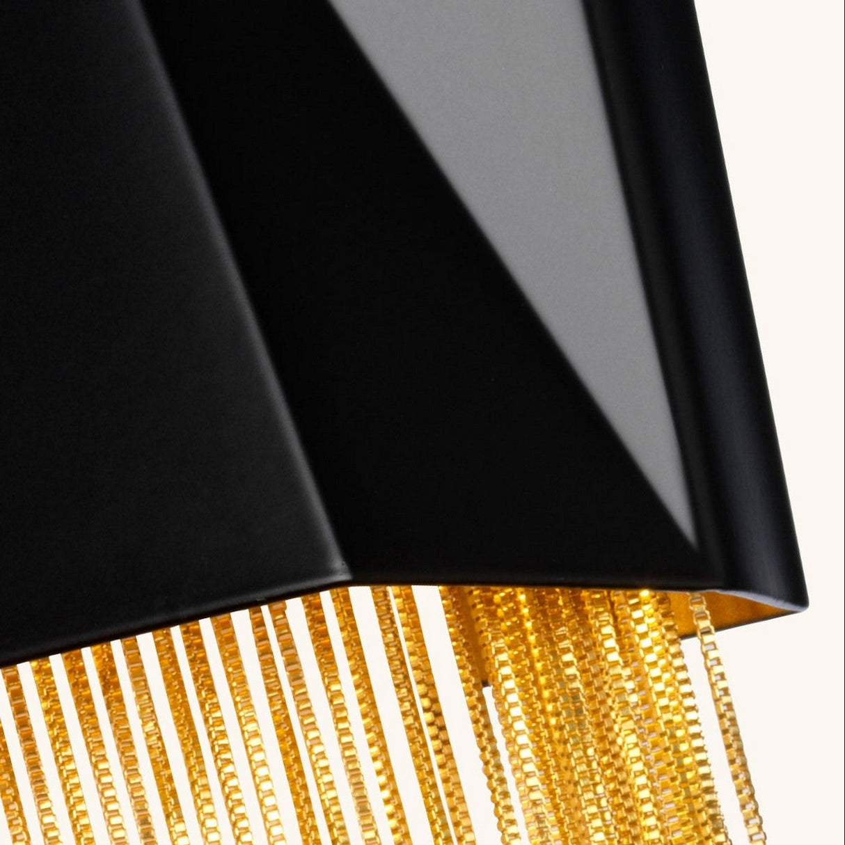 A close-up view of the Zuma 3 Light Wall Light - Satin Black/Gold features an elegant black lampshade adorned with golden fringe details. Set against a neutral background, the satin black finish enhances its luxurious design, seamlessly blending modern and classic elements with a touch of contemporary flair.