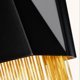 A close-up view of the Zuma 3 Light Wall Light - Satin Black/Gold features an elegant black lampshade adorned with golden fringe details. Set against a neutral background, the satin black finish enhances its luxurious design, seamlessly blending modern and classic elements with a touch of contemporary flair.