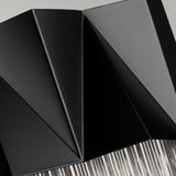 Close-up of the Zuma 3 Light Wall Light - Satin Black/Silver, featuring a modern geometric design with folded black surfaces and metallic textures, enhanced by ambient lighting to create a sleek, abstract pattern with sharp angles and lines.