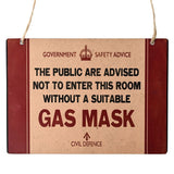 Metal wall plaque in beige and red with "Government Safety Advice", crown emblem, and bold "Gas Mask" text, hung on jute cord against a white background.