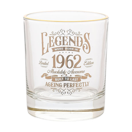 Clear round glass tumbler with gold rim, printed in gold "Legends Were Born in 1962, Ageing Perfectly" vintage label design, on a white background.