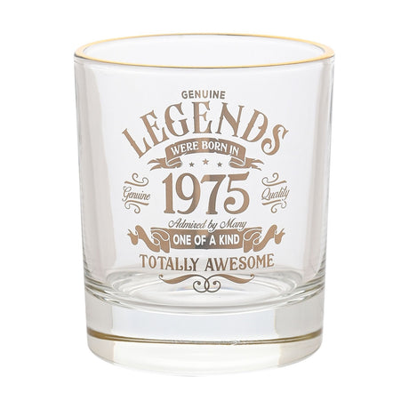 Clear glass whisky tumbler with a gold rim, featuring gold vintage-style text reading "Legends Were Born In 1975, Totally Awesome", on a plain white background.