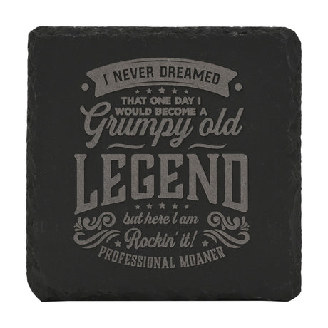 Square black slate coaster with rough-cut edges, engraved in grey with "Grumpy Old Legend... Professional Moaner" text and star details, on a white background.