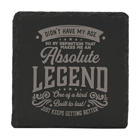 Square black slate coaster with grey engraved text reading "Didn't Have My Age Absolute Legend," framed by stars and flourishes, on a white background.
