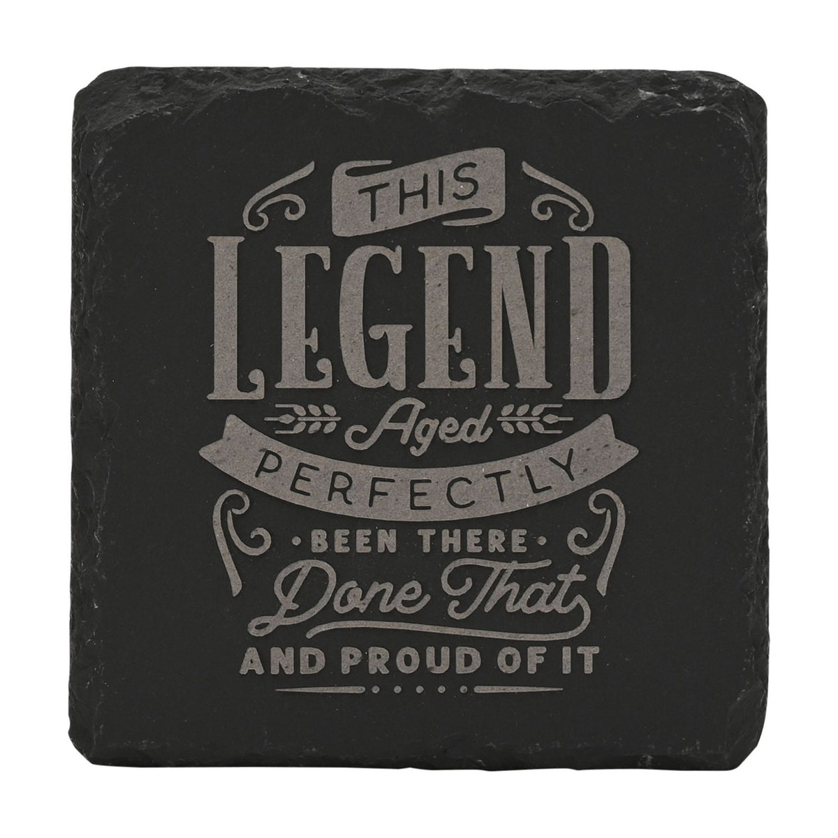 Square black slate coaster engraved with grey lettering reading This Legend Aged Perfectly, Been There, Done That and Proud of It, framed by ribbon banners and wheat sprigs.