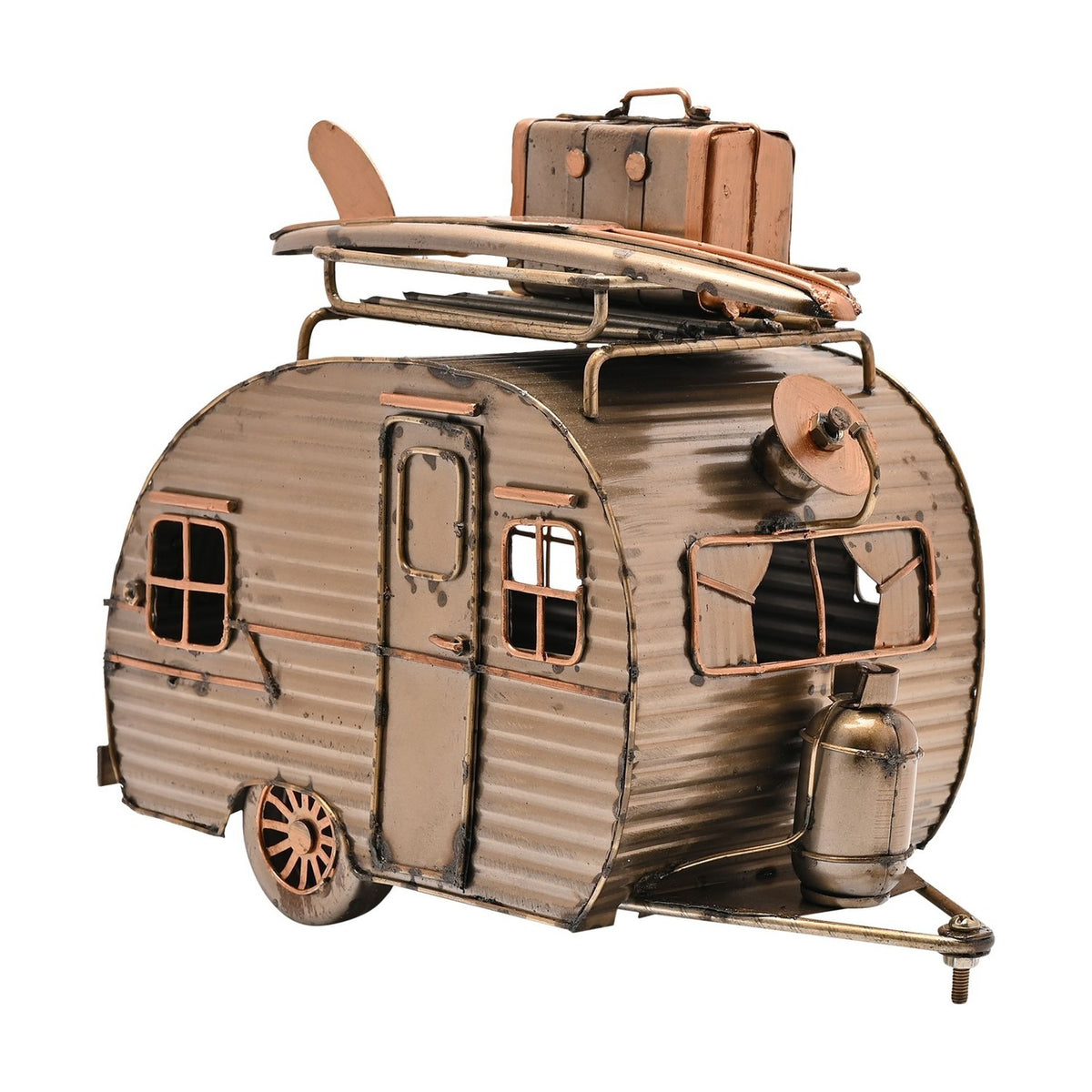 Gold metal teardrop caravan figurine with corrugated panels, door, framed windows, roof rack holding a surfboard and suitcase, and gas bottle, on a white background.