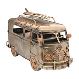 Weathered Campervan Metal Figurine with Surfboard in bronze finish, featuring a roof rack, mesh grille, round headlamps, wing mirrors and steering wheel, shown on a plain white background.