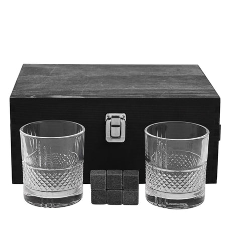 Pair of clear whisky tumblers with diamond-cut lower pattern, six dark grey whisky stones, and a black wooden gift box with silver clasp on a white background.