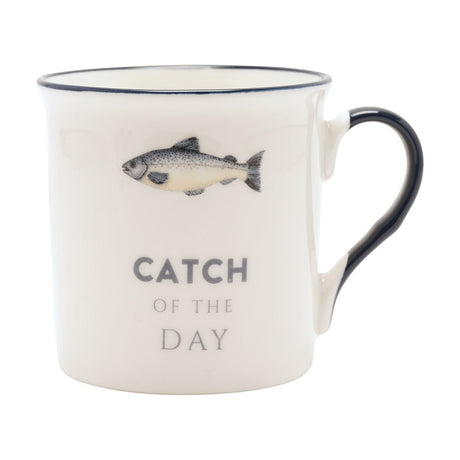 Cream porcelain mug with a navy rim and handle, featuring a grey fish illustration and "Catch of The Day" text, shown on a plain white background.
