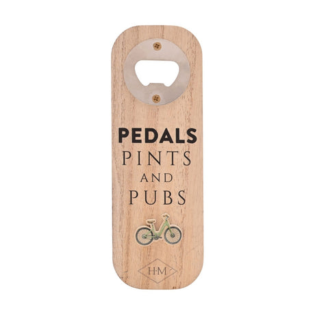 Natural wood rectangular bottle opener with a round chrome opener plate, "PEDALS PINTS AND PUBS" text, a raised green bicycle motif, and diamond monogram, shown on a plain white background.