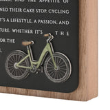 Close-up of Cycling Wooden Plaque in natural wood frame with black panel, white lettering, and a raised green bicycle design.