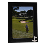 Rectangular matt black metal photo frame with a silver golf flag and ball emblem in the lower right corner, holding a 6 x 4in photo of a golfer on a course.