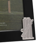 Close-up of the Cricket Stumps Metal Photo Frame 6 x 4in in black with a silver cricket stumps, bails and bat emblem on the corner, holding a pitch photograph.