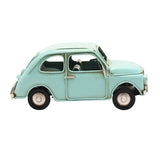 Classic car ornament metal figurine in pale aqua blue with rounded bodywork, curved roof, round headlamps and weathered seams, shown on a plain white background.