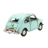 Rear-angled view of a pale aqua blue metal classic car figurine with weathered paintwork, rounded bodywork, curved roof, and chrome-effect bumper, on a plain white background.