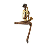 Hill Interiors brown resin figurine of a seated saxophonist with crossed legs, wearing a bowler hat and tie, playing a brass saxophone on a white background.