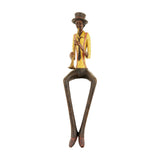 Hill Interiors Sitting Trumpeter Figurine in brown resin, seated with long legs, yellow jacket, top hat and raised trumpet, on a white background.