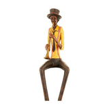 Hill Interiors Sitting Trumpeter Figurine in resin, seated pose with yellow jacket, red braces, brown top hat and trousers, playing a trumpet, on white.