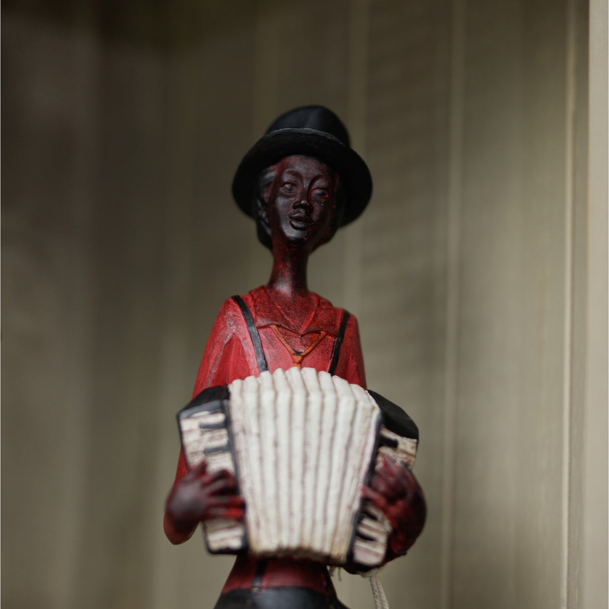 Hill Interiors Sitting Musician with Squeeze Box figurine in brown resin, wearing a black top hat and red shirt, playing a cream accordion.