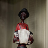 Hill Interiors Sitting Musician with Squeeze Box figurine in brown resin, wearing a black top hat and red shirt, playing a cream accordion.