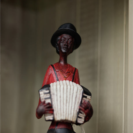 Hill Interiors Sitting Musician with Squeeze Box figurine in brown resin, wearing a black top hat and red shirt, playing a cream accordion.