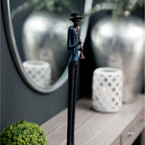 Hill Interiors Standing Trumpeter Figurine in resin with black hat, blue jacket and slim brown legs, displayed on a console beside a round mirror.